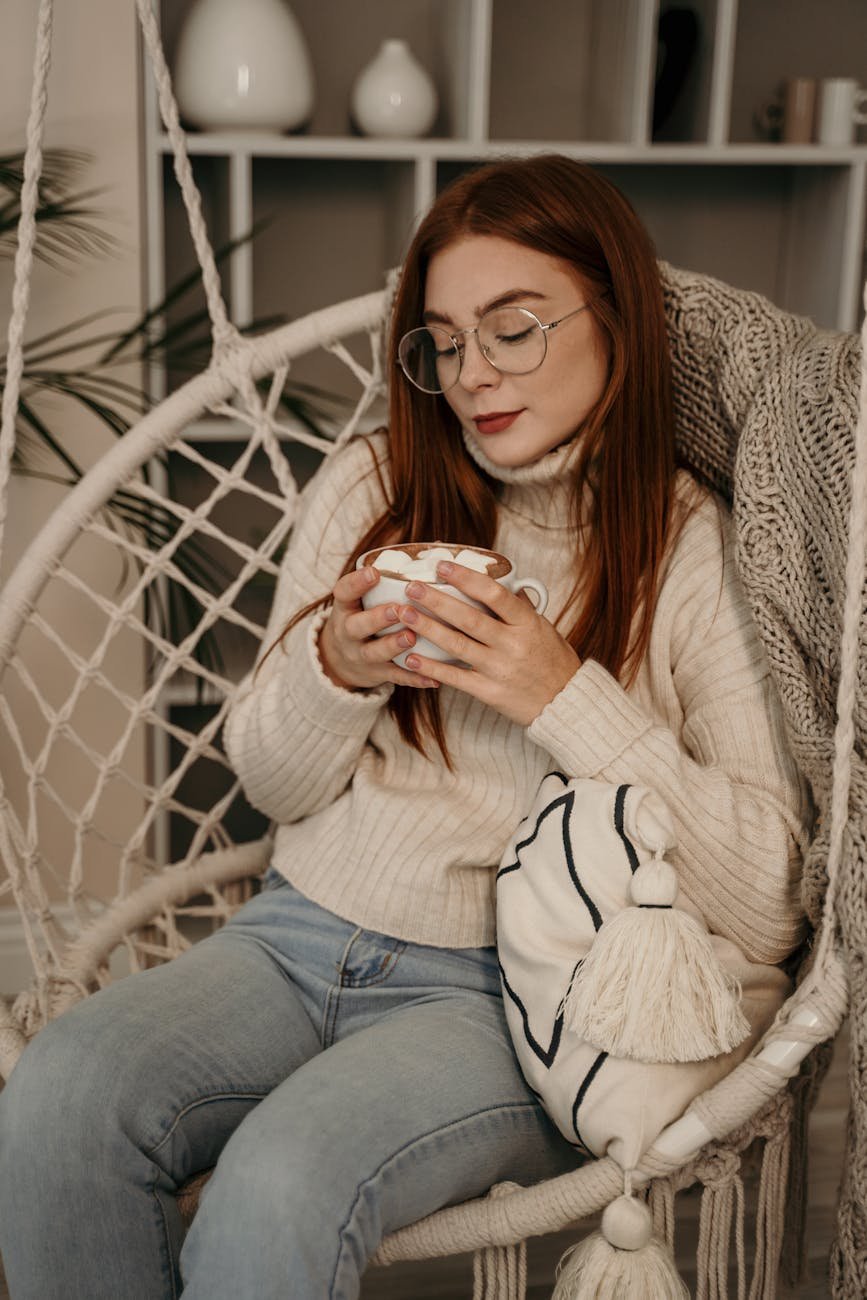 woman sitting on egg chair while holding a mug